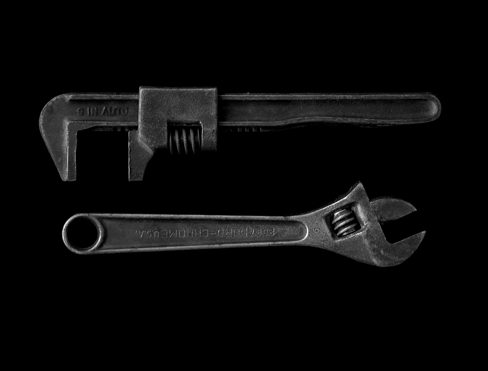 Two pipe wrenches on a black background